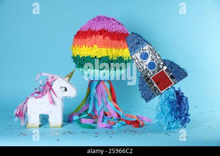 Different colorful pinatas and confetti on light blue background Stock Photo