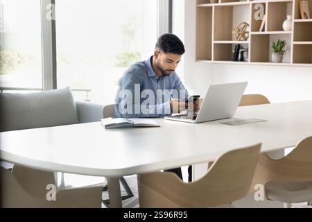 Man using smartphone seated at desk in modern conference room Stock Photo