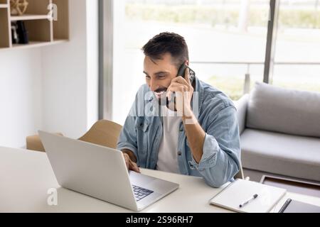 Smiling young 30s man talking on smartphone Stock Photo
