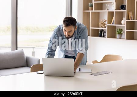 Focused businessman leaning at desk working on laptop Stock Photo