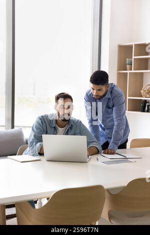 Two colleagues working on task using modern laptop Stock Photo