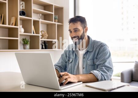 Young Hispanic man studying, e-learning, searching information using laptop Stock Photo