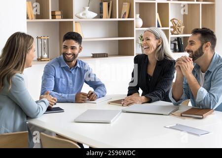 Happy workmates engaged in positive conversation gathered in boardroom Stock Photo