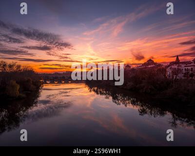 Dramatic orange, red, purple sky reflecting over the Guadalquivir river in Cordoba at sunset Stock Photo