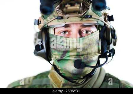 Close-up of a military soldier wearing advanced tactical gear, including a helmet and face mask, designed for communication and camouflage purposes du Stock Photo