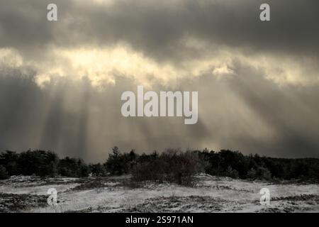 dramatic sky with storm clouds and rays of light over snowy landscape of Galvarina Plateau in Etna Park, Sicily, Italy Stock Photo