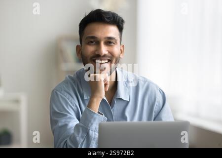 Portrait happy smiling young man sitting at workplace by notebook Stock Photo