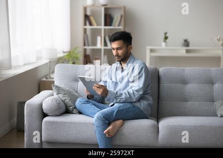 Businessman sit on sofa engaged in online communication on tablet Stock Photo