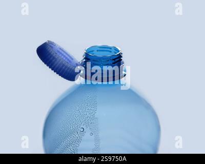 A new mechanism of plastic bottle with a stationary fixed tethered cap. Blue plastic PET water bottle with cup open close up isolated on white. Recycl Stock Photo