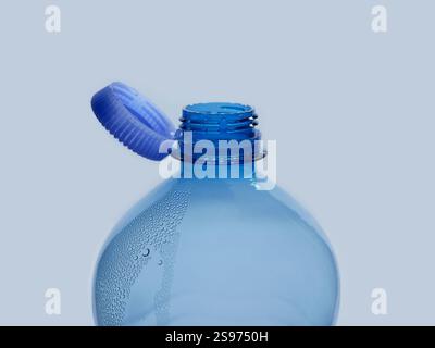 A new mechanism of plastic bottle with a stationary fixed tethered cap. Blue plastic PET water bottle with cup open close up isolated on white. Recycl Stock Photo