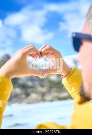 Man making heart shape with hands in winter landscape Stock Photo