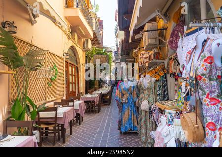 Chania Crete - August 15 2024; Cobblestone path leading between buildings typically Greek with notice board and blue chairs and walls lined with potte Stock Photo