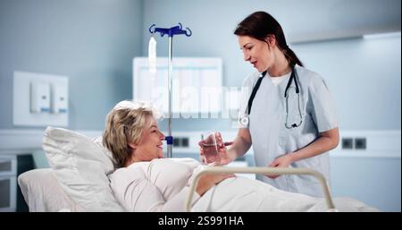 Happy Female Doctor Giving Glass Of Water To Senior Woman In Hospital Stock Photo
