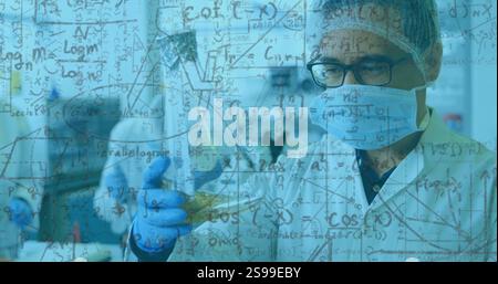 Scientific formulas and equations image over scientists conducting experiments in laboratory Stock Photo
