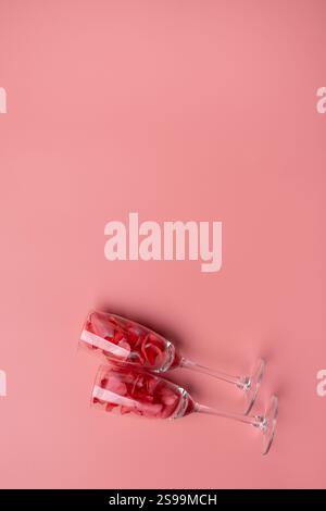 Valentine's day background, champagne glasses filled with rose petals on pink background with space for text Stock Photo