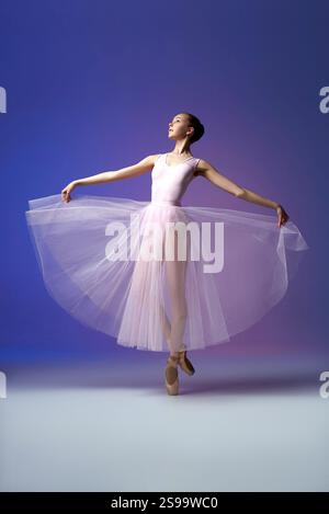 Ballet artist performs in delicate pink tutu with radiant colors, showcasing elegance and grace on pointe in studio Stock Photo