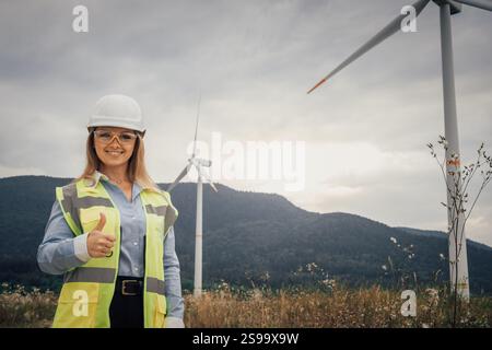 This confident female engineer is actively engaged at a wind farm, contributing to the development of renewable energy infrastructure that promotes Stock Photo