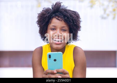 Smiling african american Young Woman Holding Smartphone Outdoors Stock Photo