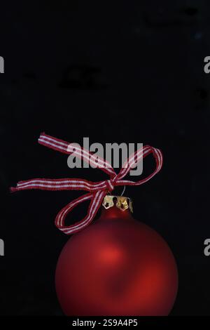 Red Christmas tree bauble with bow on a black background Stock Photo
