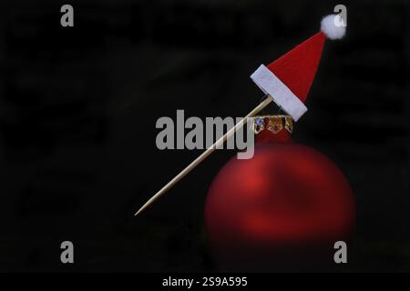 Red Christmas bauble and Christmas hat on a toothpick Stock Photo