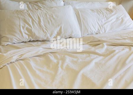 Close-up of rippled and creased white cotton bed sheets and pillows on unmade king size bed, La Spezia, Italy, Europe Stock Photo
