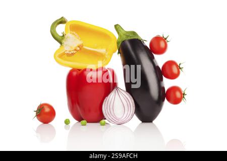 Colourful and lively abstraction: four tomatoes, three peas, two peppers, an onion and an aubergine against a white background Stock Photo