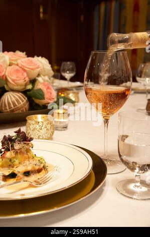 Elegantly Set Dinner Table with Wine Pouring and Candlelight Ambiance Stock Photo