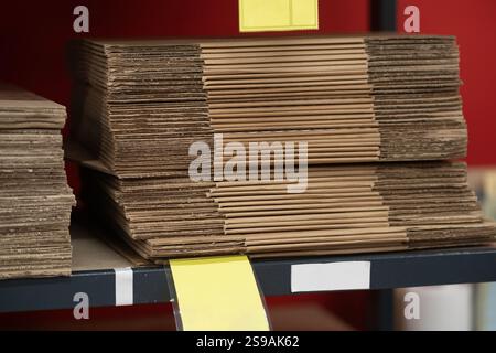 Several neatly stacked brown folders are organized on a black shelf in a workspace library. Bright red walls provide a contrasting backdrop, enhancing Stock Photo