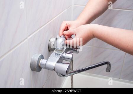 Woman changing broken shower hose in bathroom. Female plumber hands fixing hose. Plumbing concept. Male and female professions concept. Stock Photo