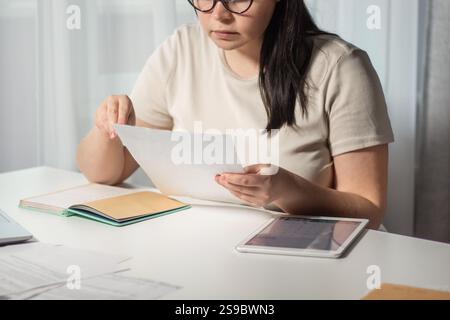Woman working remotely at home and analyzing financial documents for business. Planning business budget for year. Remote job and online business conce Stock Photo