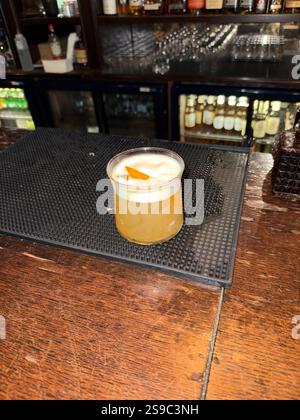 Whiskey sour cocktail served at pub bar with orange peel Stock Photo