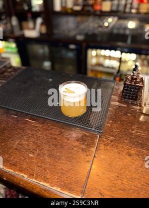 Whiskey sour cocktail served at pub bar with orange peel Stock Photo