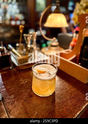 Whiskey sour cocktail served at pub bar with orange peel Stock Photo