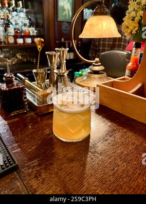 Whiskey sour cocktail served at pub bar with orange peel Stock Photo
