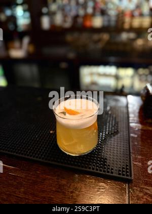 Whiskey sour cocktail served at pub bar with orange peel Stock Photo