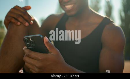 African American smiling man athletic sport guy hipster holding smartphone social media smile happy cheerful relaxed male sportsman footballer after Stock Photo
