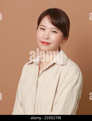Woman is wearing a shirt and sitting down. She has a red lip color. She is smiling Stock Photo