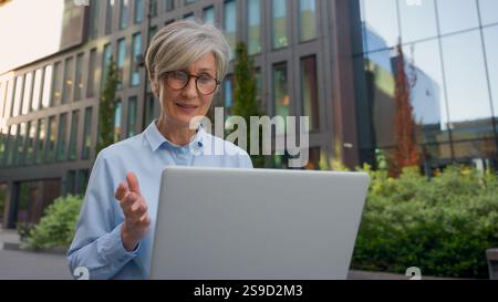 Caucasian middle aged mature woman senior old businesswoman office manager architect developer business lady working online in city typing on laptop Stock Photo