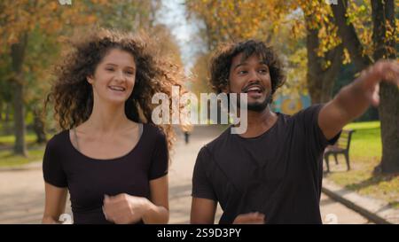 Arabian Indian Caucasian multiracial couple running together in city outdoors happy woman man jogging active healthy lifestyle morning run in park two Stock Photo