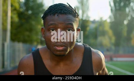 African American ethnic man guy runner jogger sprinter running on race track outdoor stadium sport ground determined male jogging morning workout run Stock Photo
