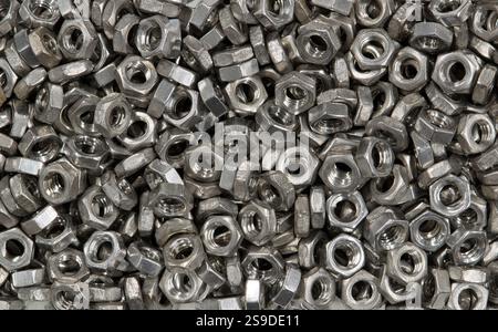 Metal nuts scattered loosely mechanical hardware fasteners machine parts work tools. Stock Photo