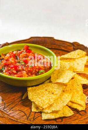 Vertical view of fresh homemade salsa made with organic tomatoes and basil in a vintage bowl and organic corn chips on an antique wood tray copy space Stock Photo