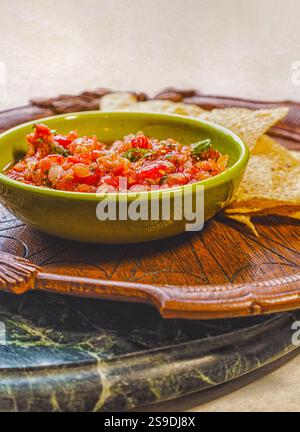Vertical view of healthy organic salsa in a vintage bowl and corn chips on an antique wooden plate on a marble tray. Stock Photo