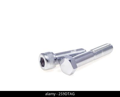 Close-up view of two metallic bolts, one featuring a hex head and the other with a socket cap head, positioned on a plain white surface, showcasing th Stock Photo