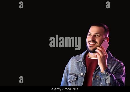 Young man talking by mobile phone on dark background Stock Photo