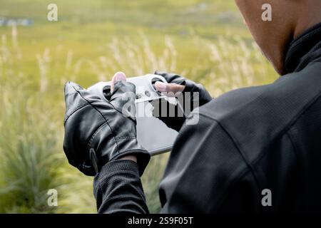 Close up view of drone operator holding remote controller in his hands. Drone flying over mountains with remote control Stock Photo