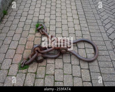 rusty mooring chain on cobbles on the quayside Stock Photo