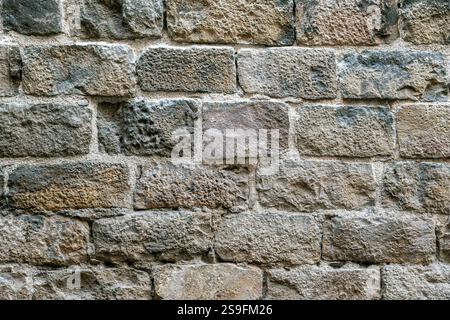 Fragment of an old wall made of rough gray stone blocks for use as an abstract background and textures. Stock Photo