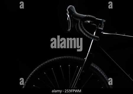 Striking silhouette of a black gravel bike with brilliant white glare effect against a deep black background. Powerful visual for cycling advertising Stock Photo
