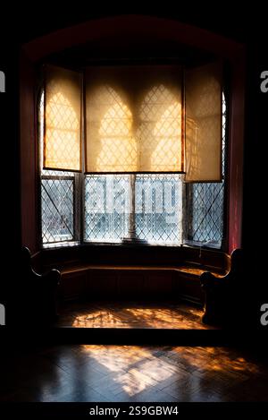 Old bow window inside an irish castle, backlit by the sun, nice reflection of light on the wooden ground Stock Photo